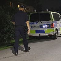 Polis går vid parkerade polisbilar