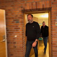 Två män går genom en dörröppning i en byggnad med tegelväggar.