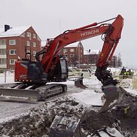 En grävmaskin arbetar med att byta utt ledningar i Kiruna.