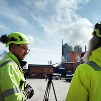 Två personer i ljusgrön varselklädsel och hjälmar vid Aspa bruk utanför Askersund, pratar om utsläpp från fabriken.