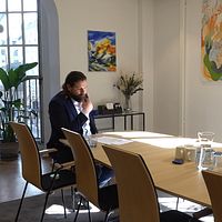 En man läser ett papper i ett soligt kontorsrum med konferensbord och konst på väggarna.