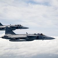 Två stridsflygplan av modell Gripen flyger ovan molntäcket.