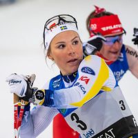 Två längdskidåkare tävlar sida vid sida i färgstarka tävlingsdräkter.