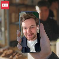 En person håller upp en mobiltelefon vid ett café.