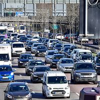 Tät trafik på flerfilig motorväg under en klar dag. Bilar och lastbilar kör i köbildning.