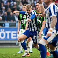 Fotbollsspelare i IFK Göteborg skjuter bollen under en match mot lag i grönsvarta tröjor.