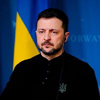 En person står framför norska och ukrainska flaggor vid en presskonferens.