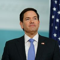 Marco Rubio i kostym framför amerikansk flagga.