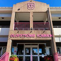 Fasaden till Olofströms kommunhus med rosa bokstäver på tegel.