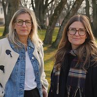 två kvinnor i glasögon i parkmiljö, hus längre bak
