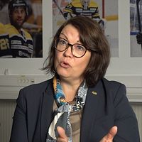 Person i kostym framför hockeybilder på väggen.