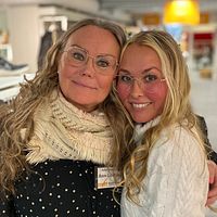 Två personer omfamnade i en butik med kläder i bakgrunden.