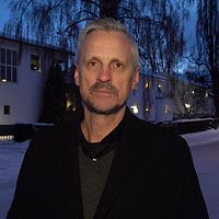 Bild på kommunpolisens Henrik Blusi utanför polisstationen i Sundsvall. I bakgrunden ser man att det är vinter och skymning och man ser ett hus.
