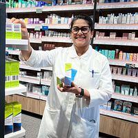 Apotekspersonal sorterar medicinförpackningar på hyllor i ett apotek.