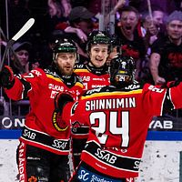 Hockeyspelare firar mål, omgivna av jublande fans i arenan.