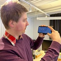 Radioreportern Hjalmar Åman visar bilden som han tog på kniven i Skellefteälven