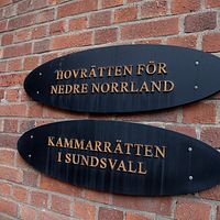 Svart skylt på röd tegelvägg där det står hovrätten för nedre norrland.