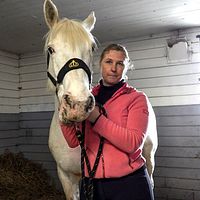Magdalena Rubensson Zäll, ridskolechef på Tibro Ryttarförening, håller i den vita hästen Betty.