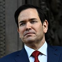Marco Rubio i kostym framför utsmyckad mörk dörr.