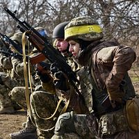 Soldater från Ukraina knäböjer i formation och håller gevär, redo för stridsövning.