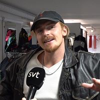 Person i läderjacka i en klädbutik, intervjuas av SVT.