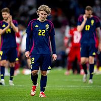Svenska fotbollsspelare i mörka uniformer går besvikna av planen.