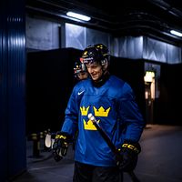 Hockeyspelare i blå Tre Kronor-tröja förbereder sig inför match i en arena.