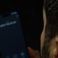 Person håller i smartphone med oidentifierat nummer på skärmen.