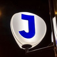 Lysande pendeltågsskylt mot svart natthimmel.