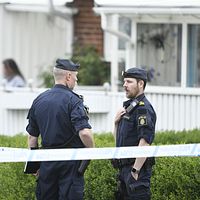 Tre poliser samtalar vid avspärrning utanför ett bostadshus i Klippan, kvinna syns i bakgrunden.