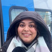 Kvinna med luva står framför ett pendeltåg