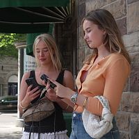 Två unga kvinnor med varsin mobil.