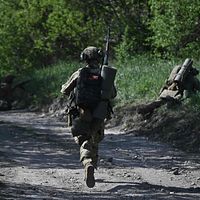 Soldater med utrustning rör sig längs en skogsväg under militäroperation.