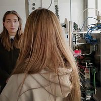 Två unga kvinnor, en reporter och en person som driver ett företag inne i en fabrikslokal utanför Göteborg med flera maskiner där det produceras lagligt knark.