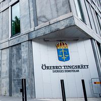 Örebro tingsrätts byggnad med dess skylt och svensk vapensköld.