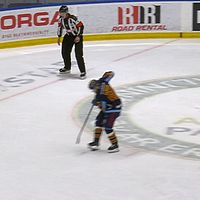 Hockeyspelare gör straffslag mot målvakt, domare står vid sidan och tittar på.