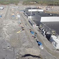 Översiktsbild över ett industriområde under byggnation med maskiner och material på marken.