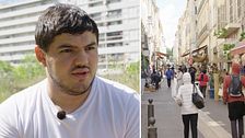 EU-valskandidaten Amine Kessaci. Man med mörkt hår och vit t-tröja. En gågata i Marseille. Fotgängare och markiser.