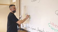 En man skriver med en tuschpenna på en whiteboard.