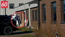 En man, Nils Thuresson, i blå jacka och kasse utanför ett tegelhus, markerad med röd cirkel.