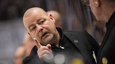 Två personer i svarta kläder diskuterar vid en sportevenemang.