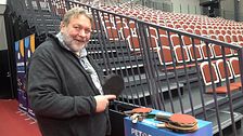 Torsten Jansson vid tom läktare håller pingisracket framför bord med fler rackets.
