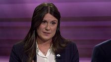 Två personer samtalar i en tv-studio med lila bakgrund.