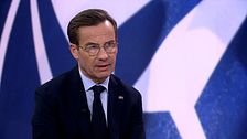Person i kostym med NATO-logotyp som bakgrund.