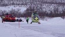 En ambulanshelikopter på marken i ett snöklätt Abisko i samband med räddningsinsatsen efter lavinolyckan där två heliskiåkare dog.