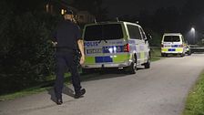 Polis går vid parkerade polisbilar