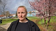 Sophie Dahlberg (V) i svart jacka står utomhus, med blommande träd och hus i bakgrunden.
