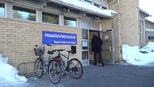 entrén till primärvårdsjouren i Umeå, en gul tegelbyggnad, en blå skylt med öppettider, en man som går in genom dörren