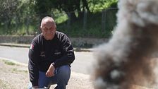 En person hukar utomhus intill en stig med rökmoln i förgrunden.