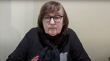 En kvinna med glasögon som pratar i en kamera